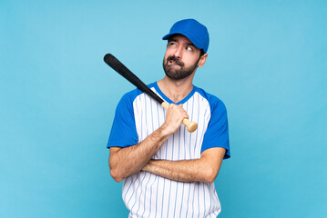 Young man playing baseball over isolated blue background with confuse face expression - obrazy, fototapety, plakaty