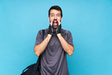 Young sport man with beard over isolated blue background shouting and announcing something