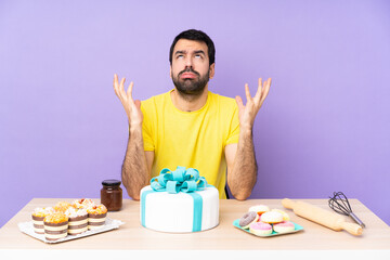 Man in a table with a big cake frustrated by a bad situation