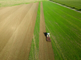 Aerial drone shot of farmer tilling field with his tractor in rural southern Germany