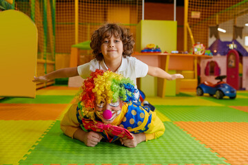 Portrait of happy smiling clown and little boy child lying on floor