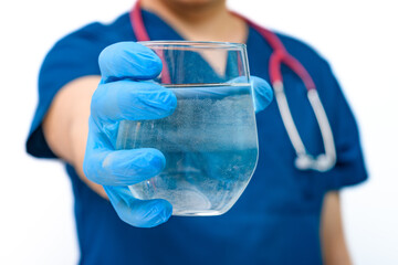 Pić wodę mineralną, lekarz trzyma szklankę pełną wody w dłoni  - obrazy, fototapety, plakaty