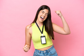 Young Brazilian woman with ID card isolated on pink background celebrating a victory
