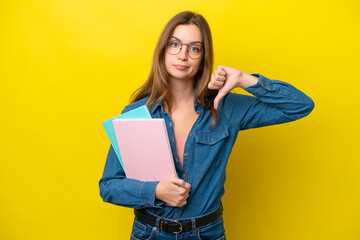 Fototapeta premium Young student caucasian woman isolated on yellow background showing thumb down with negative expression