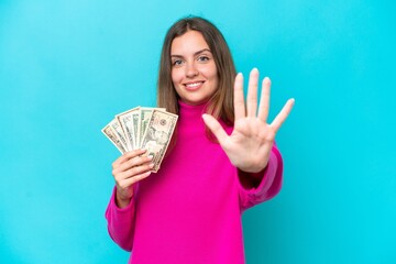 Young caucasian woman taking a lot of money isolated on blue background counting five with fingers