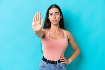 Fototapeta na wymiar Young caucasian woman isolated on blue background making stop gesture