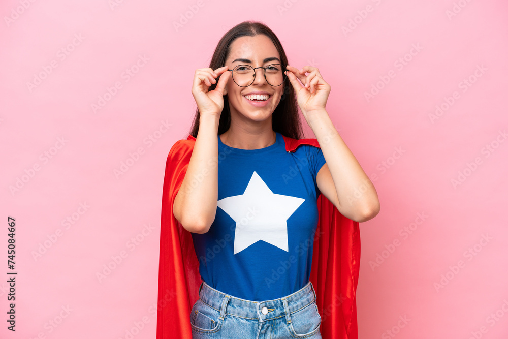 Wall mural super hero caucasian woman isolated on pink background with glasses and surprised