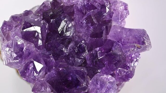 Amethyst crystals (purple quartz) sample rotating slowly against a white background.	