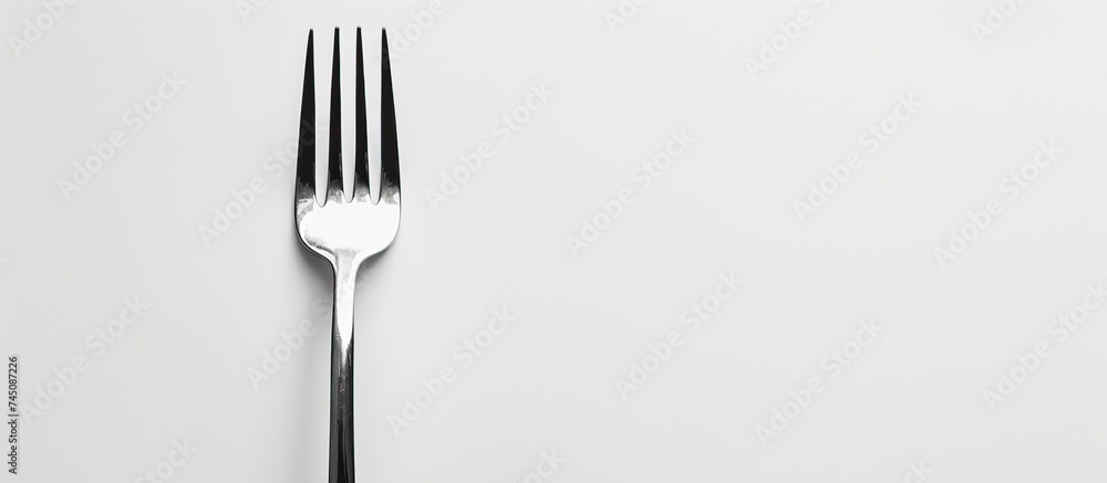 Poster a small silver fork with two prongs is placed on a clean white surface with a white background. the 