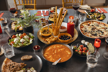 Cozy holiday table setting with different delicious food and beverages ready for friends home party