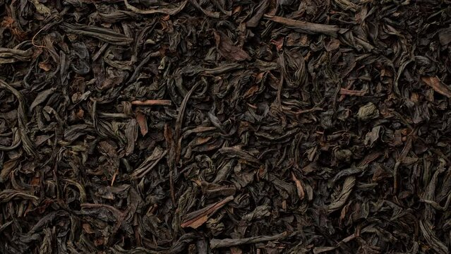 Heap of dried black tea leaves top view, slider shot
