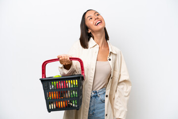 Young woman holding a shopping basket full of food isolated on white background laughing
