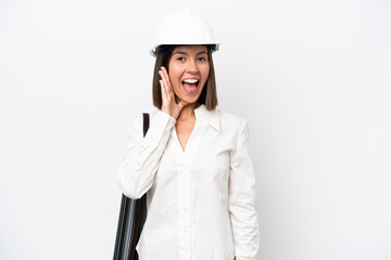 Young architect woman with helmet and holding blueprints isolated on white background with surprise and shocked facial expression
