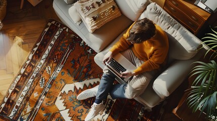 Wide Top View Apartment: Young Man Uses Laptop Sitting on a Carpet in Living Room. Creative Freelancer Working Remotely From Home. Stylish Entrepreneur doing E-Commerce Project, Online Business.