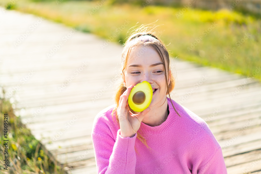 Poster Young pretty girl at outdoors holding an avocado