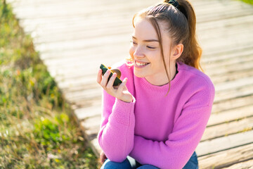 Fototapeta premium Young pretty girl at outdoors holding an avocado with happy expression
