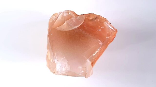 Carnelian (translucent variety of chalcedony - silicon dioxide) sample rotating slowly against a white background.	