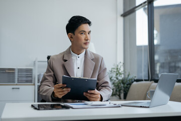 Business man working at office with laptop and documents on his desk, financial adviser analyzing data.