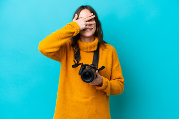 Young photographer woman isolated on blue background covering eyes by hands and smiling