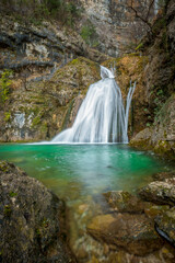 Fototapeta na wymiar Vertical photo of one of the blue pools of the Mundo River waterfall after the February outburst in Albacete, Castilla La Mancha, Spain, on a cloudy morning