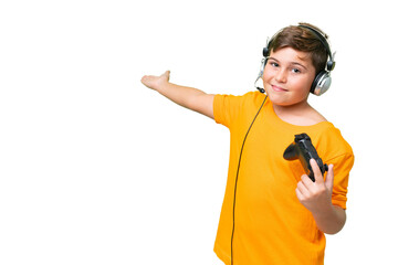 Little caucasian kid playing with a video game controller over isolated chroma key background extending hands to the side for inviting to come © luismolinero