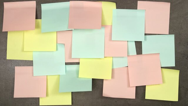 Blank colorful postit papers appearing on grey blackboard. Top view, 4K stop motion animation.