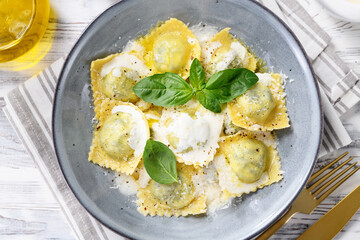 Homemade Ravioli pasta with spinach and ricotta cheese filling with creamy white sauce and grated Parmesan cheese. top view