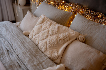 macrame pillows and a knitted blanket on the bed. Scandinavian cozy house, interior details. Boho chic style