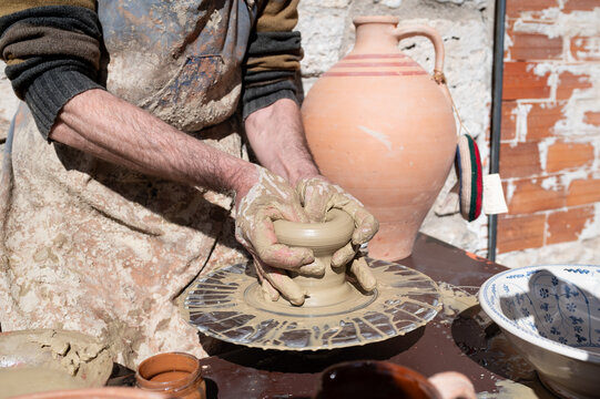 Artesano alfarero moldeando una vasija de arcilla con sus manos sobre el torno.