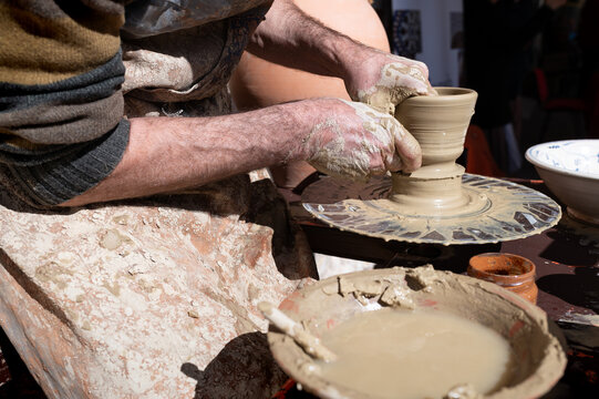 Artesano alfarero trabajando en el torno sobre una vasija de barro y arcilla.
