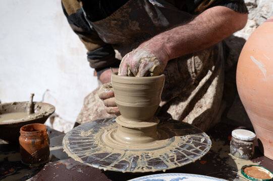 Artesano alfarero trabajando sobre una vasija de arcilla en el torno.