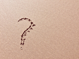 A question mark is etched into a sandy surface, symbolizing inquiry.