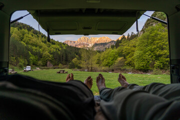 couple enjoying the sunset in the mountains from a campervan
