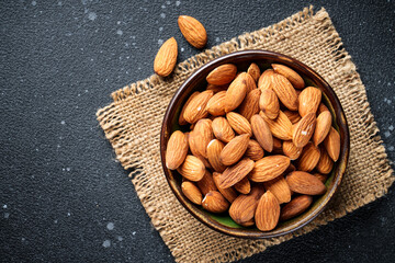 Almond nuts in bowl at black background.