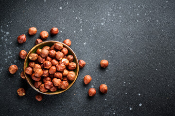 Hazelnuts in bowl at black background.