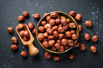 Hazelnuts in bowl at black background.