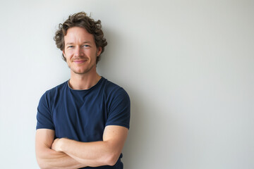 Smiling Confident Man in Dark Blue T-Shirt with Arms Crossed on Neutral Background, Modern Casual Style