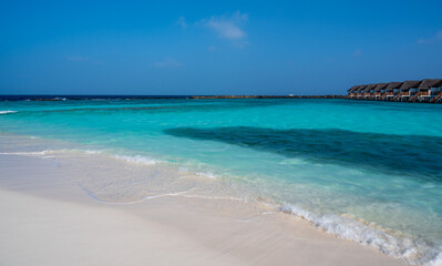 View of the pale blue water of the lagoon. In the background is a dark ocean. On the right, houses by the sea.