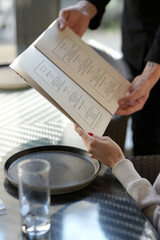 Close-up of a waiter hands giving menu to customer
