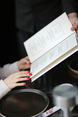 Close-up of a waiter hands giving menu to customer