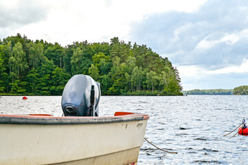 Immeln Lake, Sweden - small white motorboat with red railing and outboard engine with lake view, Immeln, Skane, Sweden	