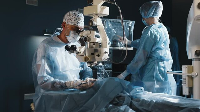 A doctor uses a microscope during eye surgery or diagnosis, cataract treatment and diopter correction. A surgeon looks through a microscope at a patient's eyes in the operating room.