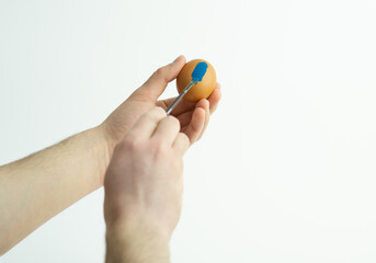 hands painting easter egg with paint brush isolated on white background. Decorating easter egg with watercolor paint.