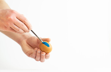 hands painting easter egg with paint brush isolated on white background. Decorating easter egg with watercolor paint.