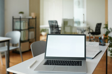 Opened laptop with empty screen on office desk of startupper