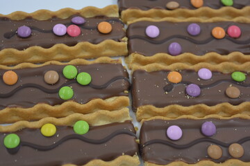 Sweets, delicious, interesting desserts, cookies with caramel, milk chocolate and small colored candies arranged on a white background.