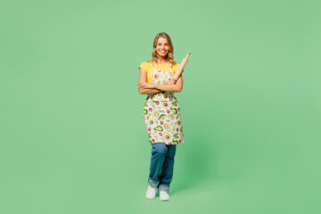 Full body young fun housewife housekeeper chef cook baker woman wear apron yellow t-shirt hold in hand rolling pin look camera isolated on plain pastel green background studio. Cooking food concept.