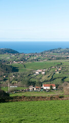 Fototapeta na wymiar Granjas en valle verde junto al océano atlántico en Asturias