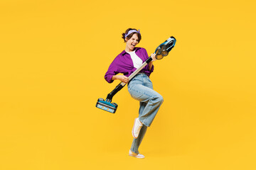 Fototapeta na wymiar Full body side view young woman wearing purple shirt casual clothes do housework tidy up hold vacuum cleaner pov play guitar isolated on plain yellow background studio portrait. Housekeeping concept.