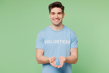 Young smiling happy fun man wear blue t-shirt title volunteer hold in hand ribbon symbol isolated...